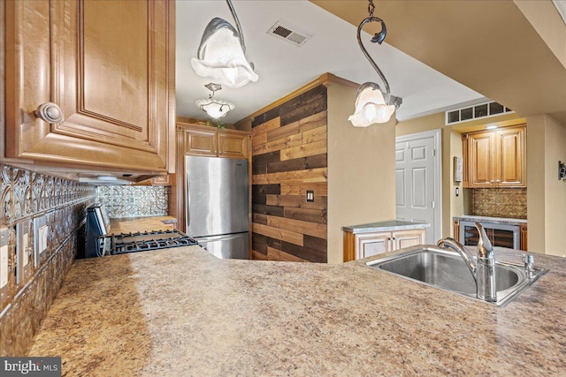 kitchen with tasteful backsplash, stainless steel appliances, sink, pendant lighting, and wood walls