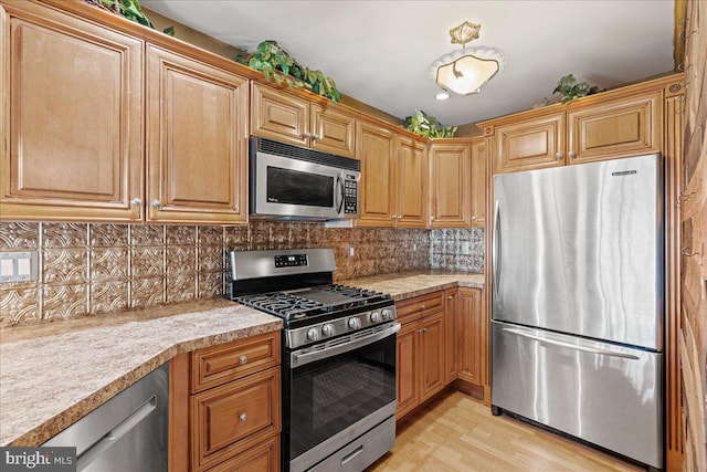 kitchen with tasteful backsplash, stainless steel appliances, and light hardwood / wood-style floors