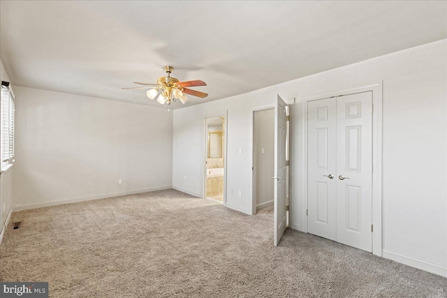 unfurnished bedroom featuring light colored carpet, ceiling fan, and ensuite bathroom