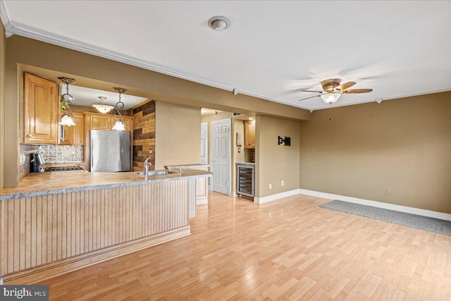 kitchen with kitchen peninsula, beverage cooler, light hardwood / wood-style flooring, stainless steel refrigerator, and hanging light fixtures