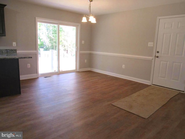 unfurnished dining area with dark hardwood / wood-style floors and a chandelier