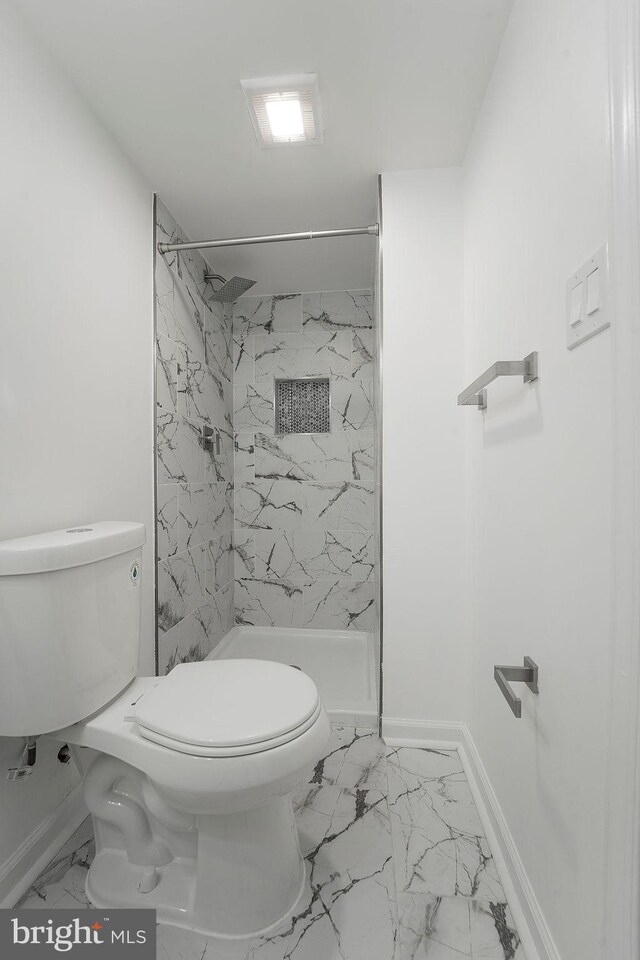 bathroom featuring a tile shower and toilet