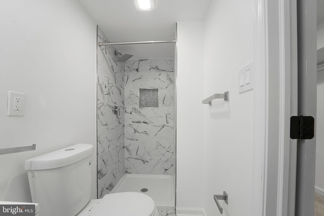 bathroom with a tile shower and toilet