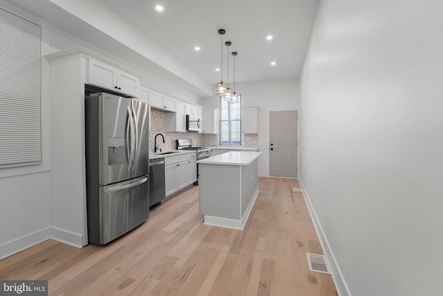 kitchen featuring decorative light fixtures, sink, white cabinets, a center island, and stainless steel appliances