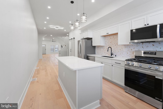 kitchen with a center island, white cabinetry, sink, decorative light fixtures, and stainless steel appliances