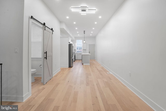 hall with light hardwood / wood-style flooring and a barn door