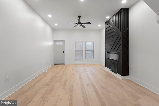 unfurnished living room featuring light hardwood / wood-style floors, a large fireplace, and ceiling fan