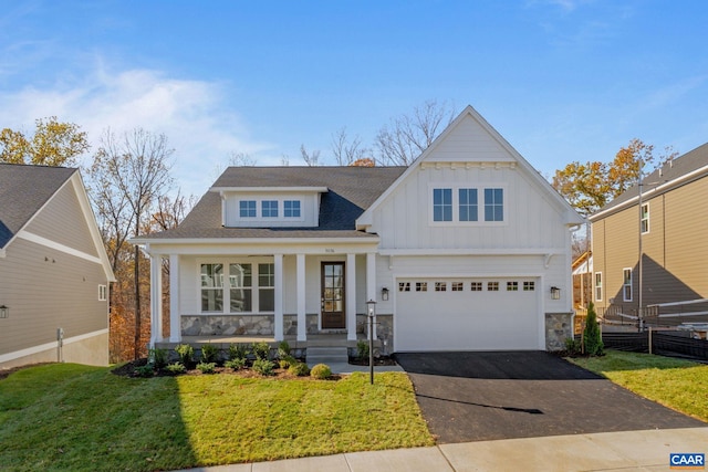 view of front of home with covered porch, a front yard, and a garage