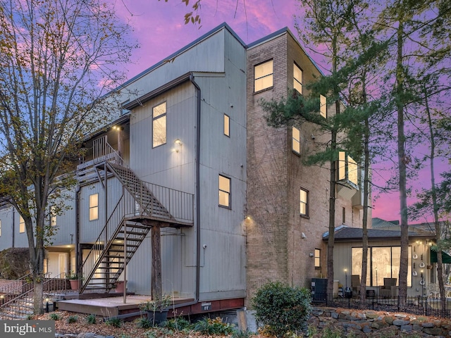 back house at dusk with a balcony and central AC unit