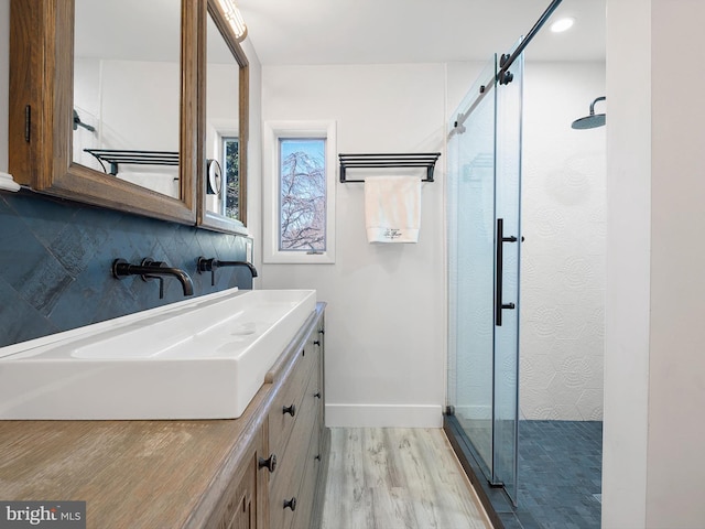 bathroom featuring hardwood / wood-style flooring, vanity, an enclosed shower, and backsplash