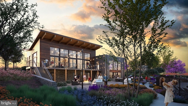 back house at dusk featuring a patio area and a balcony