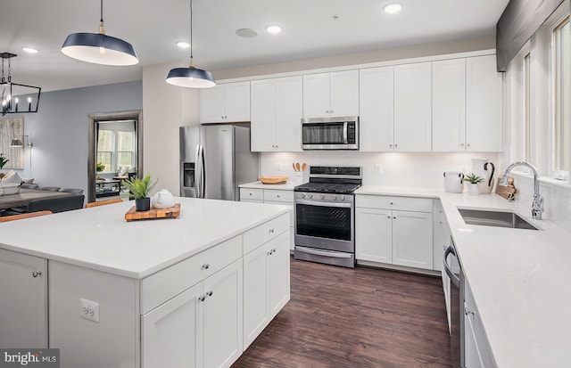 kitchen featuring stainless steel appliances, dark wood-type flooring, sink, white cabinets, and a center island