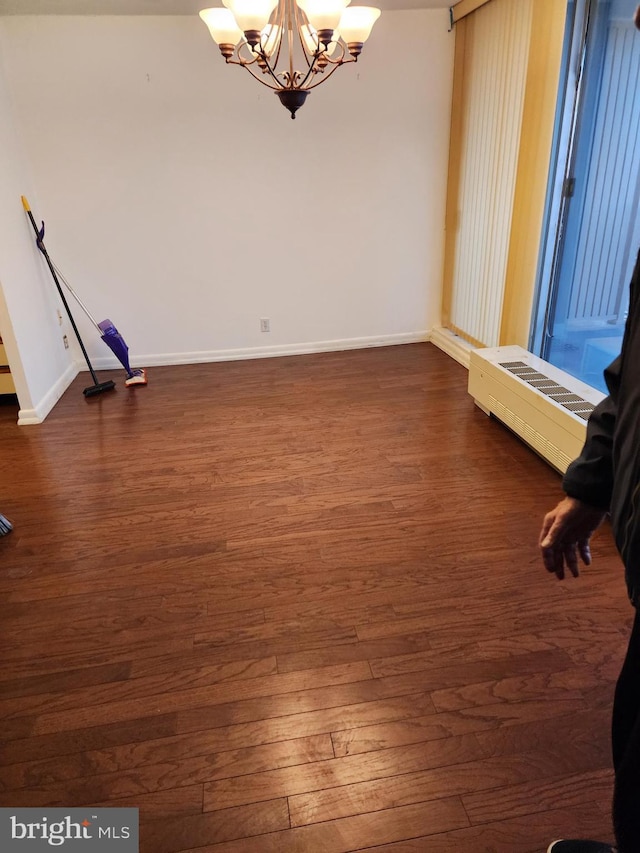 empty room featuring an inviting chandelier and dark wood-type flooring