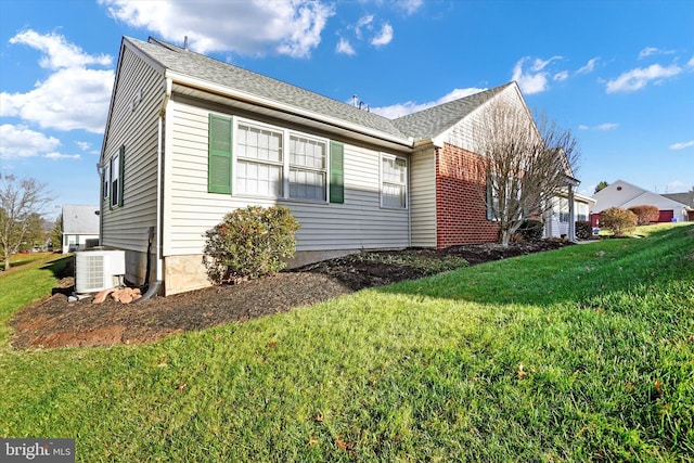 view of side of home featuring central AC unit and a lawn