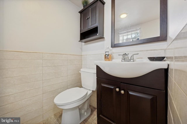 bathroom featuring vanity, tile walls, and toilet