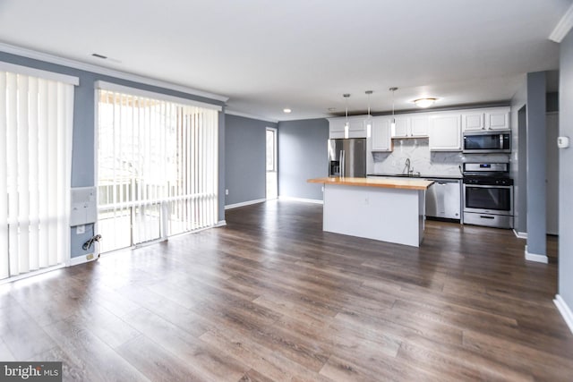 kitchen with stainless steel appliances, butcher block countertops, white cabinets, dark hardwood / wood-style floors, and a kitchen island