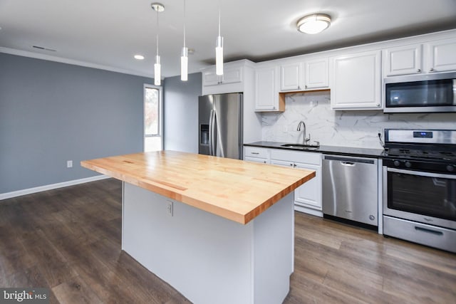 kitchen with wood counters, white cabinets, sink, hanging light fixtures, and appliances with stainless steel finishes