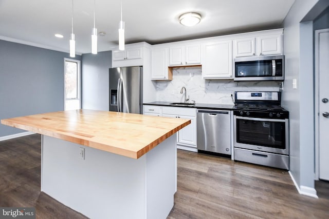 kitchen with wood counters, decorative light fixtures, stainless steel appliances, and white cabinetry