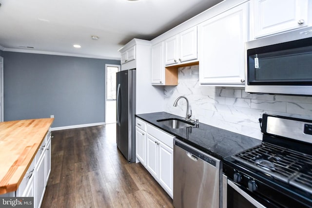 kitchen featuring appliances with stainless steel finishes, dark wood-type flooring, sink, white cabinets, and butcher block countertops