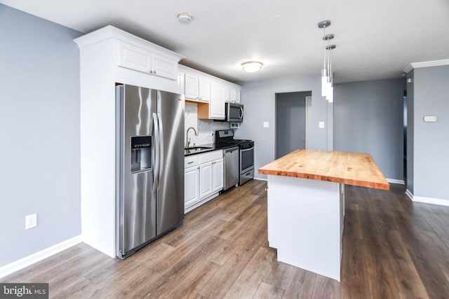 kitchen with pendant lighting, wooden counters, white cabinets, sink, and stainless steel appliances