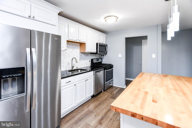 kitchen with wood counters, appliances with stainless steel finishes, sink, hardwood / wood-style flooring, and white cabinetry