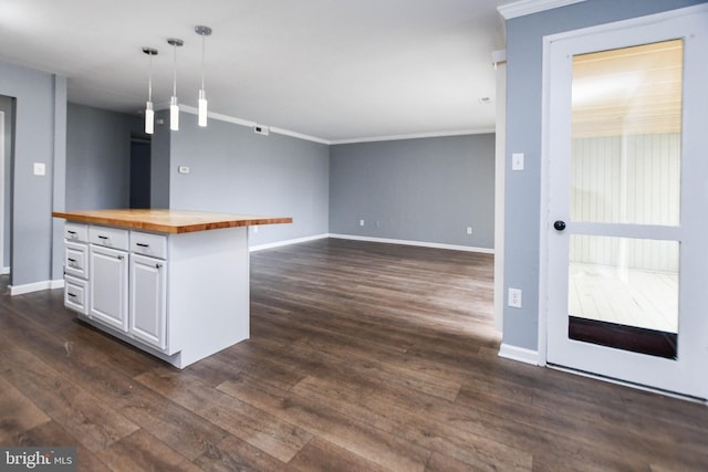 kitchen with dark wood-type flooring, wood counters, pendant lighting, white cabinets, and ornamental molding