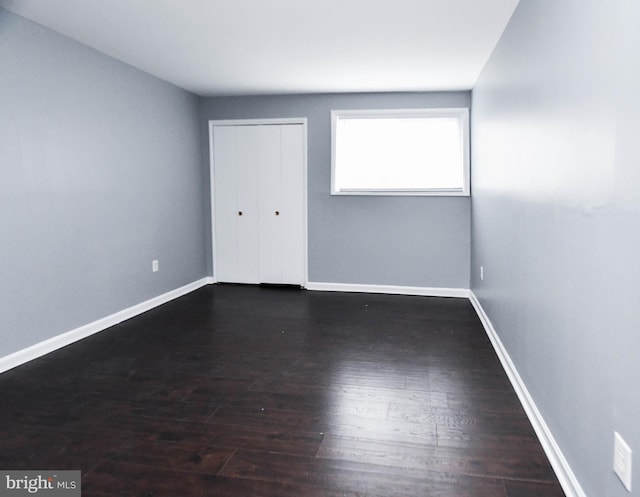 unfurnished bedroom with a closet and dark wood-type flooring