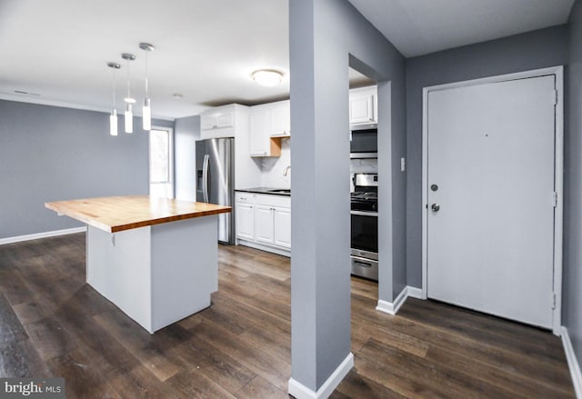 kitchen with pendant lighting, wood counters, a center island, appliances with stainless steel finishes, and white cabinetry