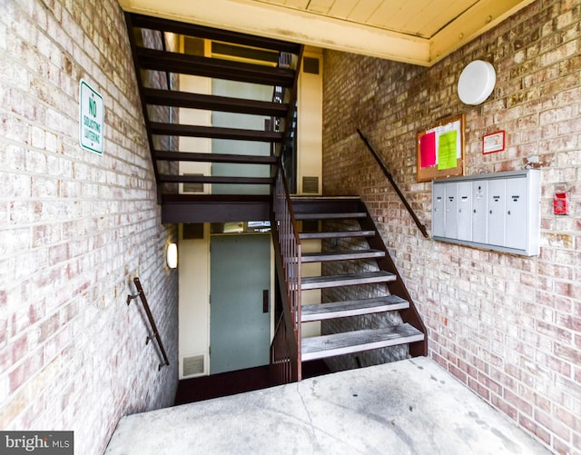 stairs featuring a mail area and brick wall