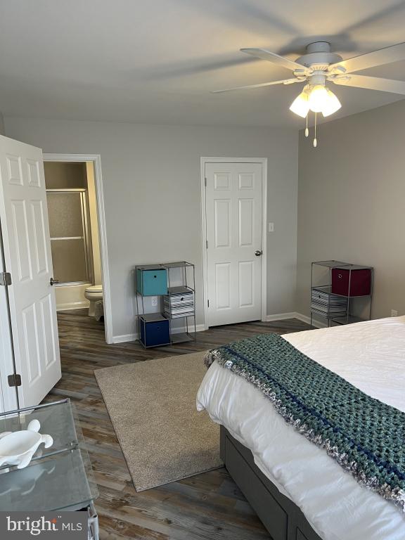 bedroom with ceiling fan, dark hardwood / wood-style floors, and connected bathroom