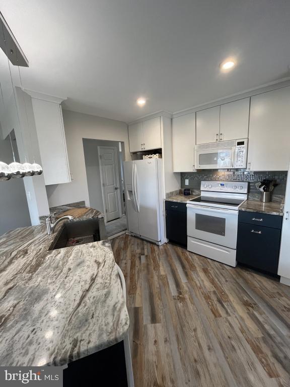 kitchen with dark hardwood / wood-style flooring, tasteful backsplash, white appliances, sink, and white cabinets