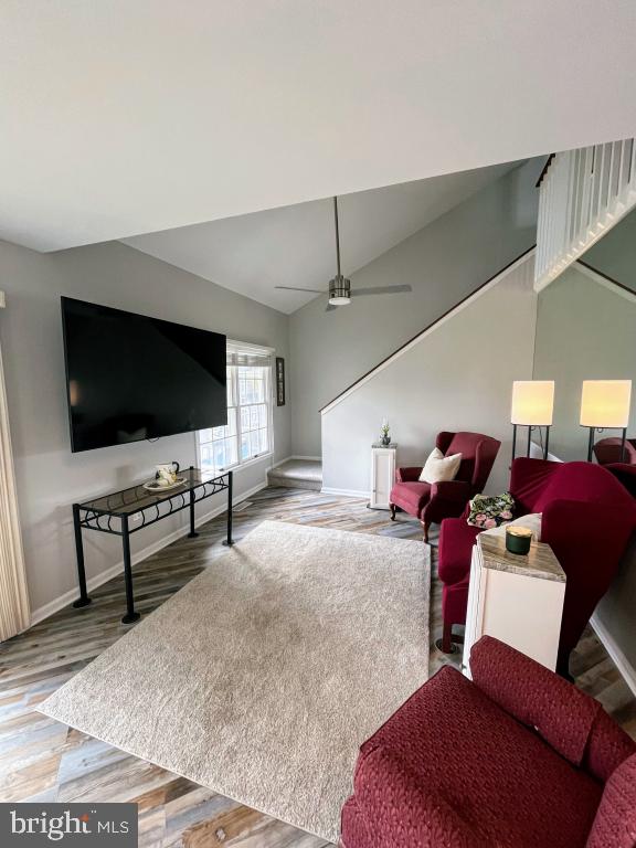 living room with hardwood / wood-style floors, vaulted ceiling, and ceiling fan