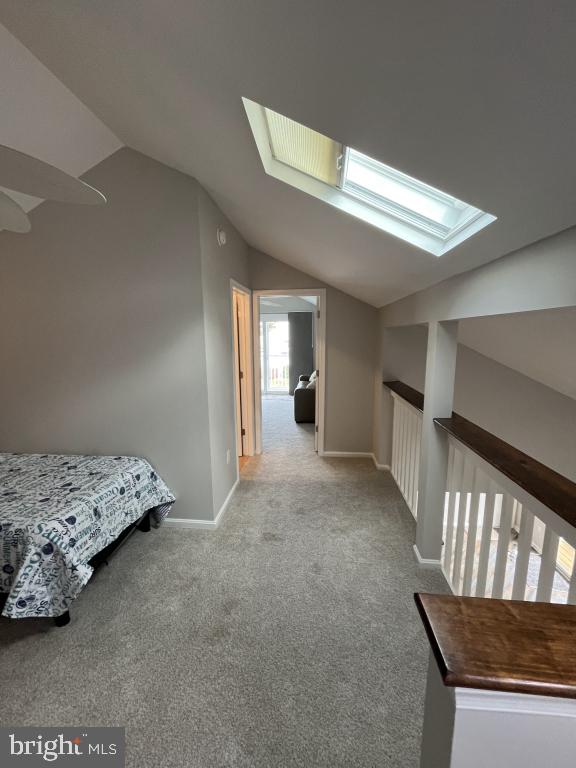 interior space with vaulted ceiling with skylight and light carpet