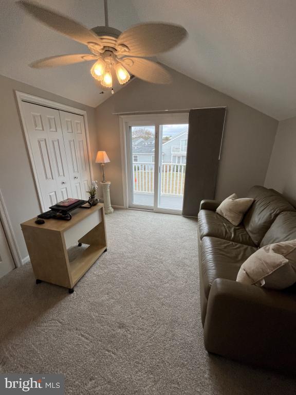 living room featuring carpet flooring, ceiling fan, and lofted ceiling