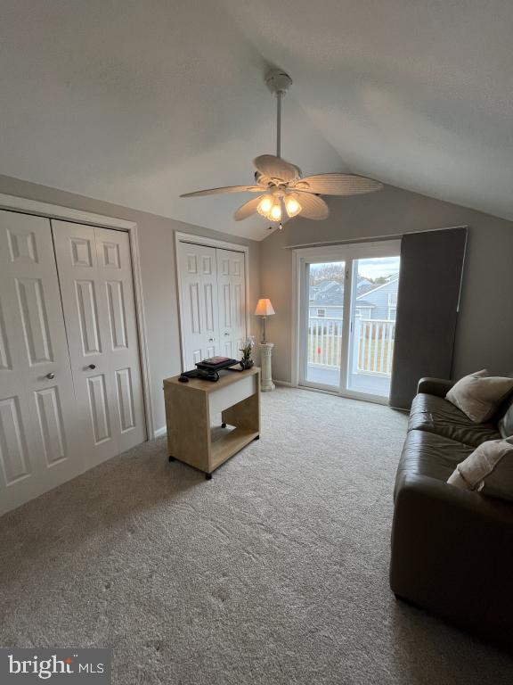 living room featuring ceiling fan, carpet floors, and vaulted ceiling