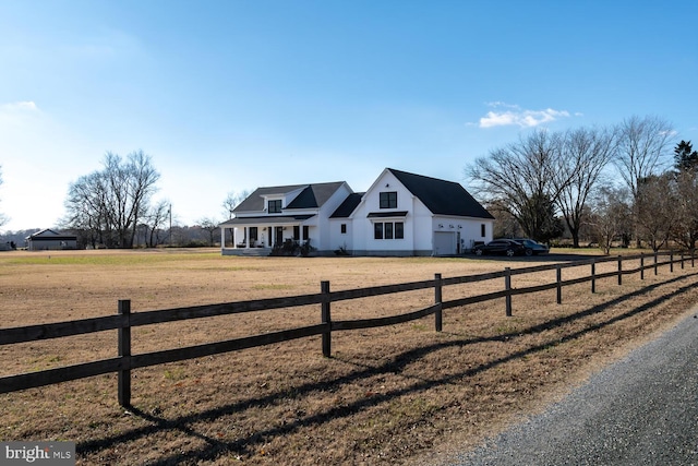 view of front facade featuring covered porch, a rural view, a garage, and a front lawn