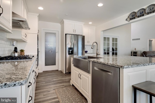 kitchen featuring white cabinetry, ventilation hood, light hardwood / wood-style floors, and appliances with stainless steel finishes