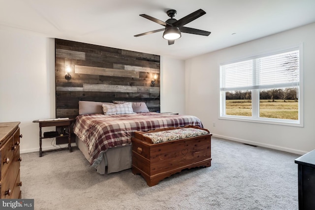 bedroom with ceiling fan, light colored carpet, and wooden walls