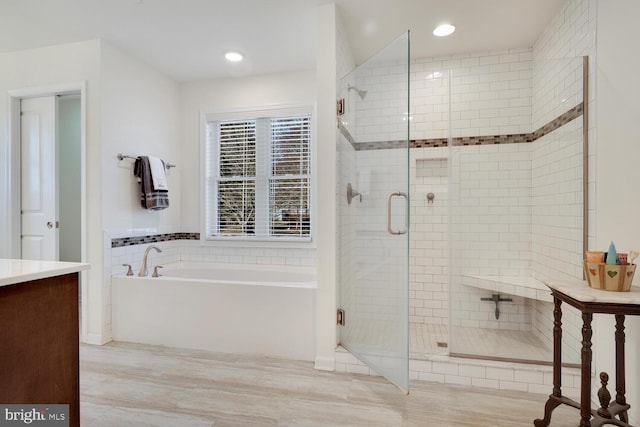 bathroom with vanity, wood-type flooring, and shower with separate bathtub