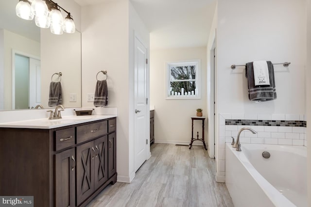 bathroom with vanity, wood-type flooring, and a bath