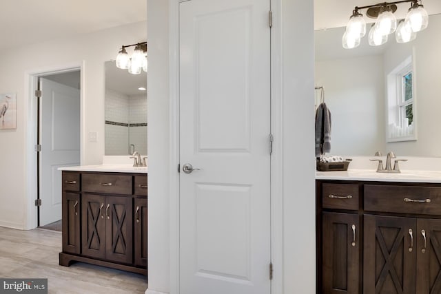 bathroom with wood-type flooring, vanity, and a tile shower