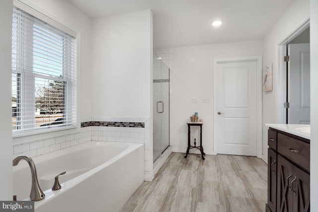 bathroom featuring plus walk in shower, vanity, and hardwood / wood-style flooring