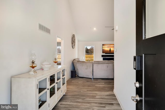 hall with hardwood / wood-style floors and high vaulted ceiling