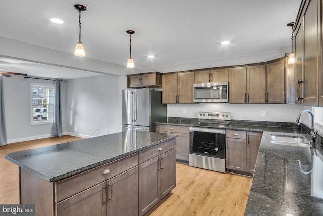 kitchen featuring dark stone counters, stainless steel appliances, sink, light hardwood / wood-style flooring, and a kitchen island