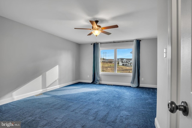 spare room featuring dark colored carpet and ceiling fan