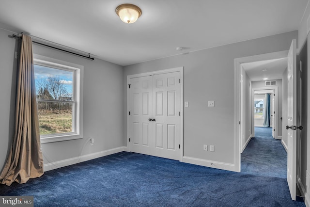 unfurnished bedroom with a closet and dark colored carpet