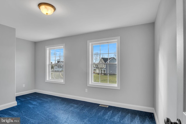 spare room featuring plenty of natural light and dark carpet