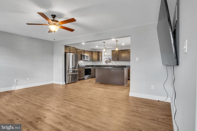 kitchen with stainless steel appliances, ceiling fan, pendant lighting, light hardwood / wood-style flooring, and a center island