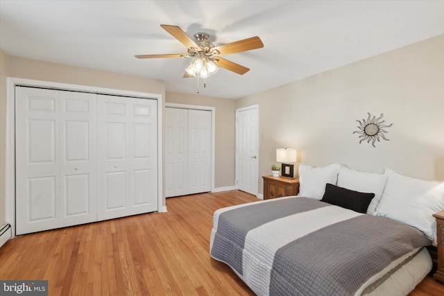 bedroom featuring multiple closets, ceiling fan, and light hardwood / wood-style flooring