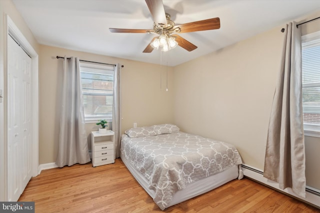 bedroom featuring a closet, a baseboard radiator, ceiling fan, and light hardwood / wood-style floors